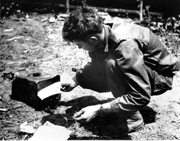Message center code operator burns classified material in order to maintain maximum security. Note improvised incinerator made of discarded tin can.
